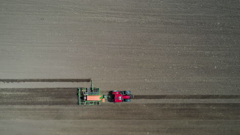 Red-tractor-driving-in-the-farm-field-filmed-from-above