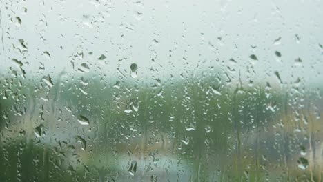 Regentropfen-Gleiten-An-Regnerischen-Tagen-Langsam-Auf-Fensterglas,-Mittlere-Nahaufnahme
