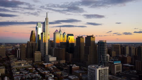 Aerial-pull-back-timelapse-of-the-Philadelphia-skyline-during-a-colorful-sunset-showcasing-the-tall,-advanced-buildings-and-urban-development