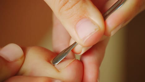Pedicurist-Scraping-Big-Toe-Nail-With-A-Cuticle-Pusher---close-up