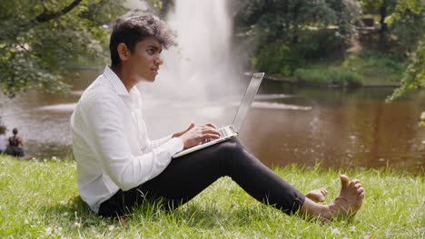 Indian-businessman-working-remotely-from-park-with-fountain
