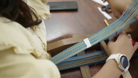 Woman-hand-weaving-patterns-using-blue-and-yellow