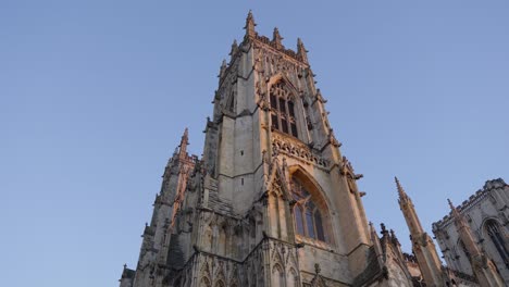 Wide-angle-parallax-looking-up-at-the-main-tower-on-huge-stone-cathedral-York-Minster-on-a-clear-sunrise