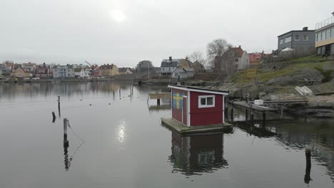 A-close-view-of-a-picturesque-little-saunaraft-with-a-swedish-flag-hanging-outside,-standing-on-still-water-in-Karlskrona,-Sweden