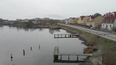A-scenic-view-of-small-wooden-bridges-on-still-water-with-cars-driving-by-on-the-street-with-the-beautiful-swedish-houses-on-Salto-in-Karlskrona,-Sweden
