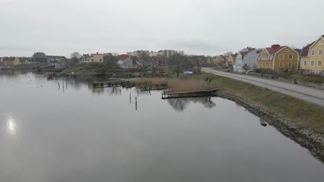Ein-Malerischer-Blick-Auf-Kleine-Holzbrücken-Auf-Stillem-Wasser,-Eine-Vogelgruppe,-Ein-Saunafloß-Und-Die-Schöne-Insel-Ekholmen-Von-Karlskrona,-Schweden-Im-Hintergrund