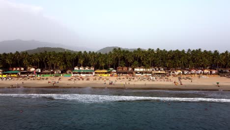 Drohne-Fliegt-über-Das-Ufer-Eines-Strandes-An-Einem-Tropischen-Sonnenstrand-Mit-Touristen,-Indien,-Goa,-Palolem