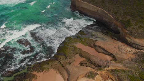 4k-Aerial-rocky-beach-near-cliff-with-blue-water-Drone-jib-down-shot