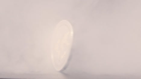 Ripple-coin-spinning-in-slow-motion-through-smoke