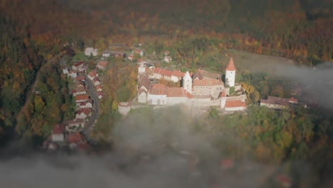 A-medieval-castle-Krivoklat-is-rising-on-a-hill-surrounded-by-woods,-with-a-village-at-its-bottom