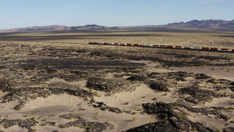 Extremely-long-freight-train-speeds-quickly-down-a-completely-straight-train-track-through-a-desert-landscape