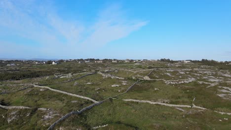 Farmers-Houses-In-Connemara-Near-Coral-Strand-Beach-With-Fields-Divided-By-Walls-Made-From-Rocks-Under-The-Bright-Blue-Sky-In-Ireland