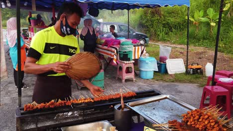 Hombre-Asiático-Cocinando-Satay-En-El-Puesto-Del-Mercado-Con-Mascarilla