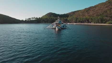 Aerial-Fly-Through-Shot-Of-A-Small-Passenger-Boat-Parked-Near-An-Island-In-Palawan-Philippines
