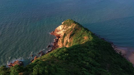 Lush-tropical-Lantau-island-hilltop-slope-to-ocean-coastline-aerial-rising-pull-back