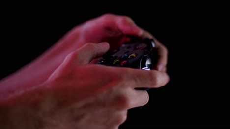 Playing-video-games-in-a-darkened-room-with-a-black-background-close-up-on-a-controller-buttons-playing-quickly