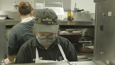 McDonald's-restaurant-employee-at-work-in-kitchen-during-COVID-coronavirus-pandemic-wearing-face-mask-slow-motion