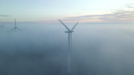 Vista-Aérea-De-La-Producción-De-Energía-De-Turbinas-Eólicas-Con-Nubes-Bajas-En-Una-Mañana-Nublada