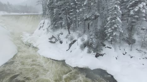 Spectacular-winter-wonderland-scene-filmed-by-drone-flying-over-flowing-river