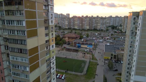 Aerial-view-between-old-soviet-made-apartment-buildings,-revealing-a-soccer-field,-in-a-indigent-slum-neighborhood-of-Kyiv,-during-sunset,-in-Kiev,-Ukraine---rising,-drone-shot