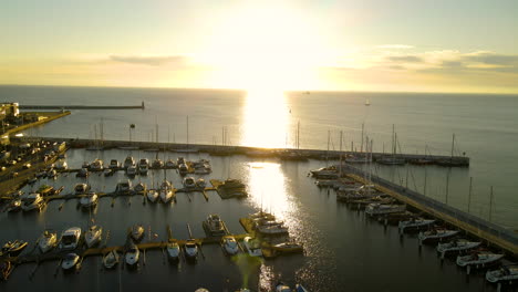 Atemberaubender-Sonnenuntergang-über-Dem-Jachthafen-Von-Gdynia-Voller-Segelboote,-Während-Das-Sonnenlicht-Vom-Ruhigen-Meerwasser-Reflektiert-Wird,-Drohnenantenne