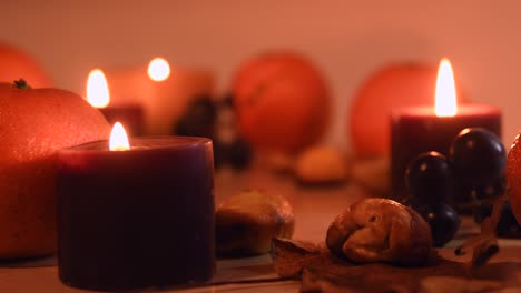 Close-up-of-an-autumnal-setting-with-leaves,-mandarin,-chestnuts,-grapes-and-candles