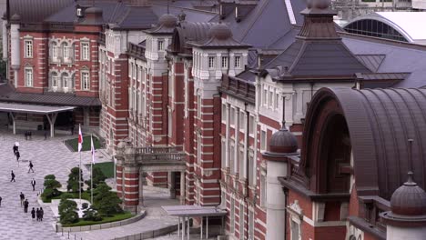Tight-long-shot-of-Tokyo-station-from-high-above-with-some-people-walking-in-front-of-it-at---Slow-motion-shot