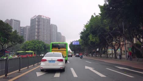 Car-front-view-of-the-green-bus-and-traffic-on-busy-street-in-the-city-of-Chongqing-in-summer,-central-China