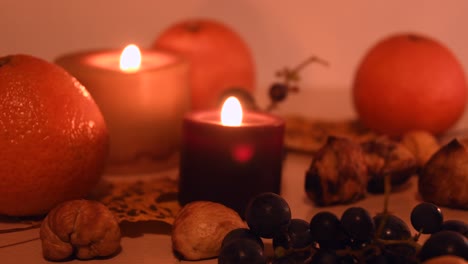 Nahaufnahme-Eines-Herbstlichen-Hintergrunds-Mit-Blättern,-Mandarinen,-Kastanien,-Kerzen-Und-Trauben