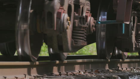 Extreme-closeup-of-freight-train-wheels-on-a-train-track-passing-by-camera