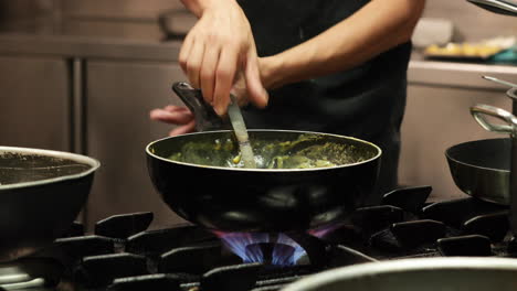 Chef-Rociando-Sal-En-Una-Salsa-Espesa-Y-Luego-Revolviéndola-A-Fuego-Medio-En-Una-Estufa-De-Gas-En-La-Cocina-De-Un-Restaurante