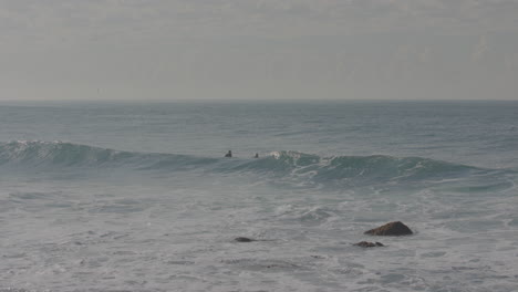 Tres-Surfistas-Esperan-En-El-Agua-A-Que-Llegue-Una-Ola,-Luego-Uno-Encuentra-Una-En-La-Playa-Manly-Australia