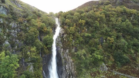 Idyllic-Snowdonia-mountain-range-Aber-falls-waterfalls-national-park-aerial-push-in-to-cliff-edge-view