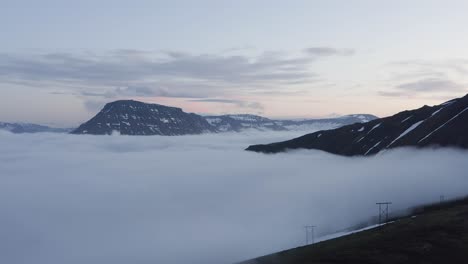 Panoramic-view-of-Reyðarfjörður-fjord-covered-in-thick-low-clouds,-aerial