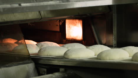 Fresh-Batch-Of-Bread-Dough-Placed-Unto-Oven-By-Baker---slow-motion-shot