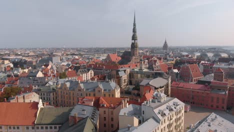 Drone-aerial-flying-towards-St-Peter's-Church-tower-over-buildings-in-Riga,-Latvia