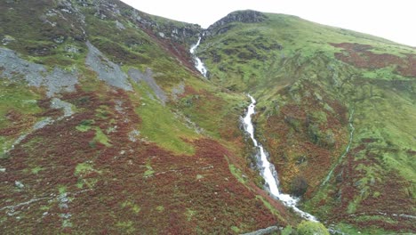 Idyllic-Snowdonia-mountain-range-Aber-falls-waterfalls-national-park-aerial-pull-back-orbit-left-view