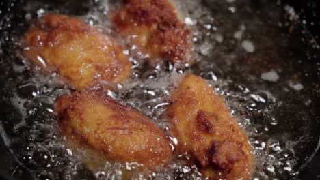 Four-Crispy-Spanish-Croquetas-Deep-Fry-in-Bubbling-Oil,-Close-Up