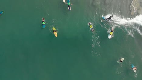 Vertical-aerial-footage-showing-beginners-and-advanced-level-surfers,on-their-surf-boards,surfing-on-water