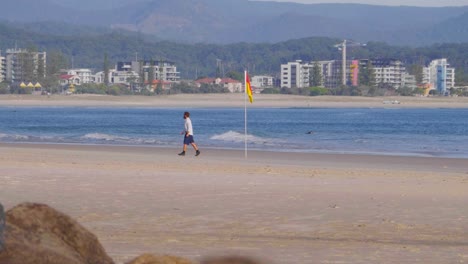 Man-Leaving-The-Beach-After-Putting-Lifeguard-On-Duty-Flag-At-Snapper-Rocks---Ocean-Waves-At-Rainbow-Bay---Coolangatta,-Gold-Coast,-Queensland,-Australia
