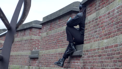 Girl-sitting-on-wall-outdoor-on-dutch-castle-and-listening-music