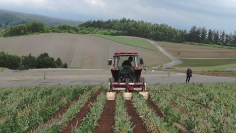 Farm-Tractor-Moving-Through-Land-Field-in-Japanese-Village,-Back-View