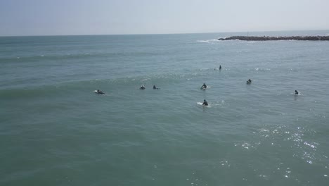 Aerial-slow-panning-shot-of-surfers-and-swimmers