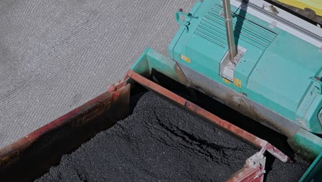 Close-up-dump-truck-laying-asphalt-The-black-crushed