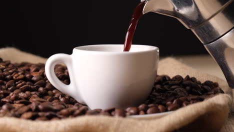 Kaffee-Aus-Der-Moka-Kaffeemaschine-Auf-Jute-Leinwand-Und-Kaffeebohnen-Gießen