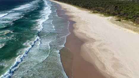 Beautiful-drone-shot-of-ocean-and-beach-at-Bryon-Bay-Australia,-tilting-up-shot
