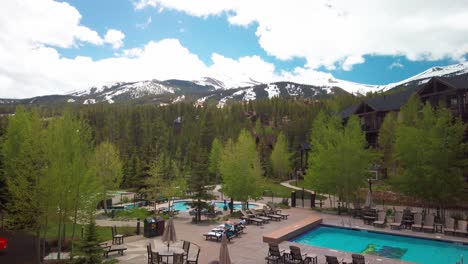 Wide-tilting-up-shot-from-resort-pool-to-the-Rocky-Mountain-peaks-in-the-summer