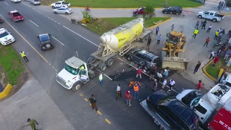 Aerial-view-of-people-and-a-bulldozer-clearing-a-traffic-accident,-collision-incident,-in-Mexico,-Central-America---orbit,-drone-shot
