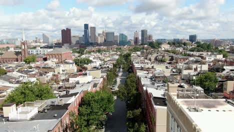 Cinematic-aerial-pullback-reveals-expanse-of-Baltimore-skyline-from-Federal-Hill-neighborhood,-colonial-historic-houses-line-street-during-summer-day