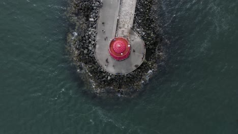 Top-down-view-fly-by-of-people-walking-around-The-Poolbeg-Lighthouse